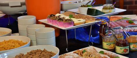 A buffet with various food items including pastries, cereals, and condiments.