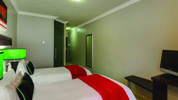 A hotel room with two beds, a desk, a television, and a mirror.