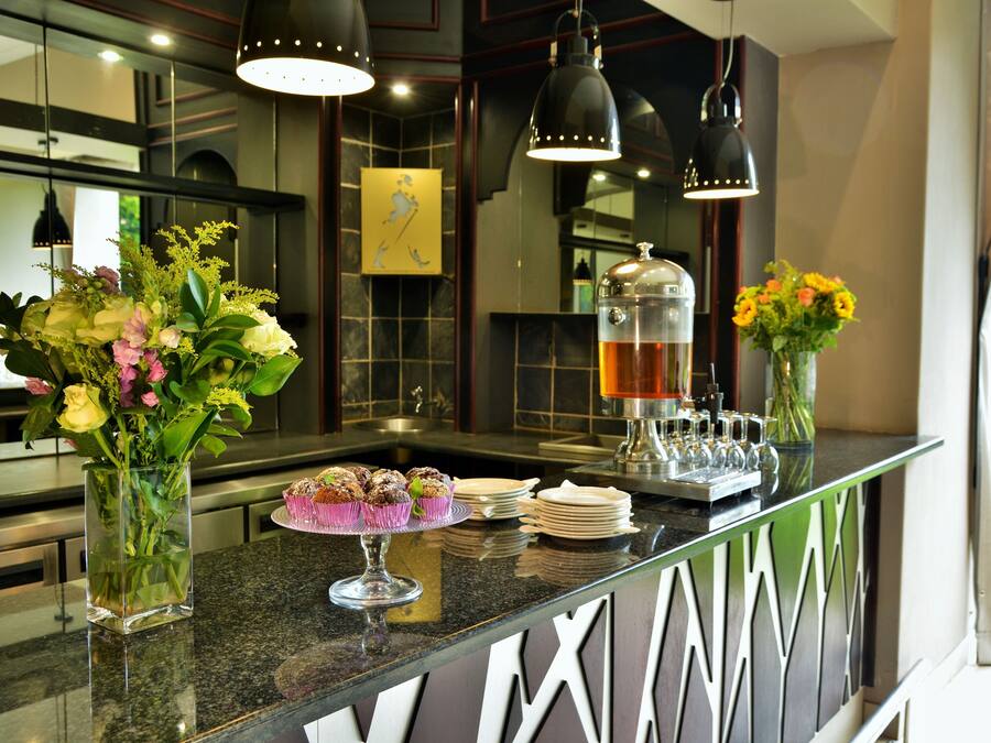 A modern kitchen with a marble countertop, a coffee machine, and a vase with flowers.