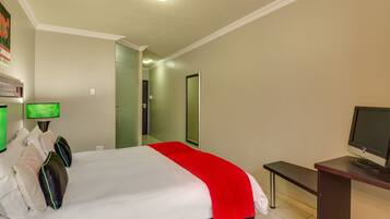 A hotel room with a bed, a desk, a television, and a mirror.