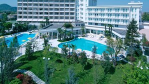 Un hôtel doté de nombreux balcons, d’une piscine et d’un aménagement paysager luxuriant.