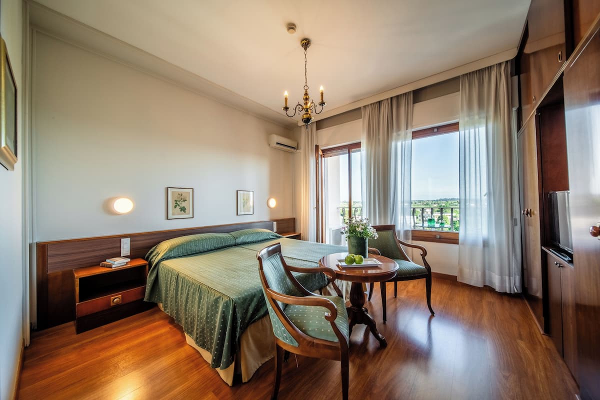 Habitación de hotel con cama, muebles de madera, una mesa de comedor y vistas a través de la ventana.