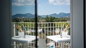 Un balcon avec des tables dressées pour le dîner, offrant une vue sur un paysage montagneux avec des bâtiments visibles au loin.