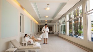 Un espace spa avec des fauteuils inclinables et une personne en peignoir debout.