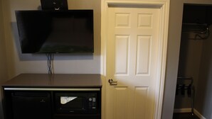 A room with a flat-screen TV mounted on the wall, a microwave, and a refrigerator. - Layne Hotel (San Francisco)