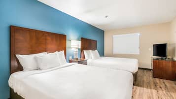 Quarto de hotel com duas camas, televisão e secretária.