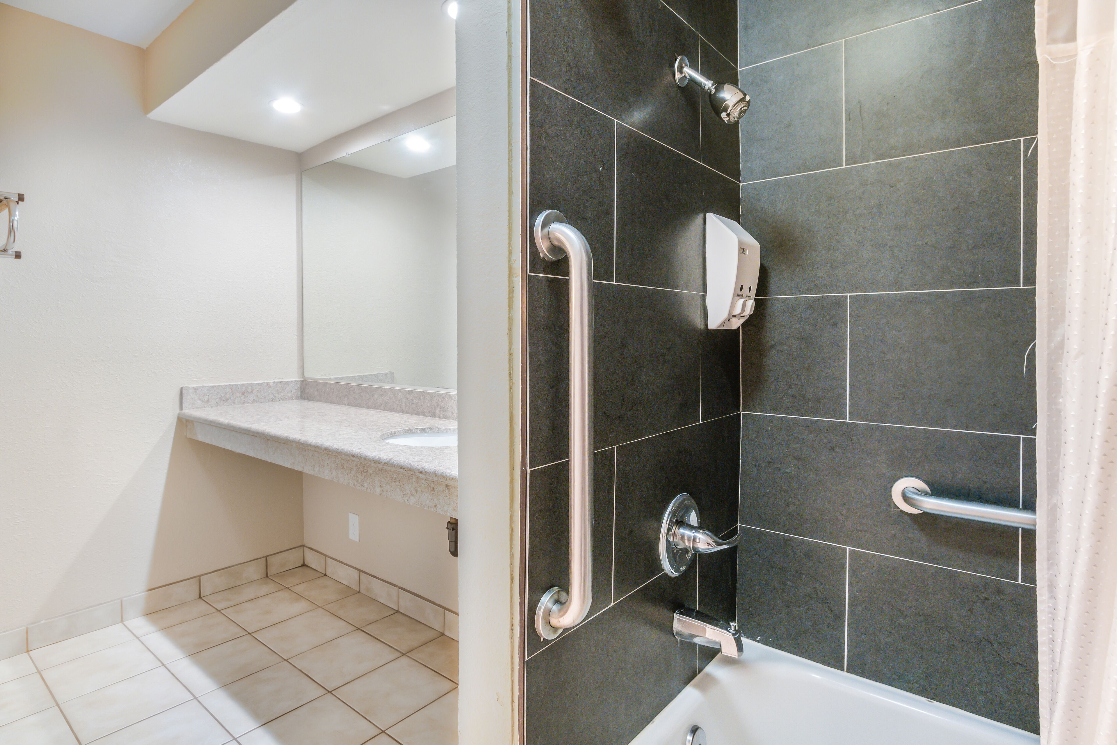 A modern bathroom with a shower, grab bars, and a vanity.