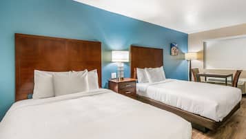 A hotel room with two beds, a desk, and a chair.