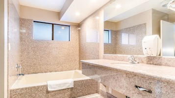 A modern bathroom with a freestanding bathtub, granite countertops, and a large mirror.