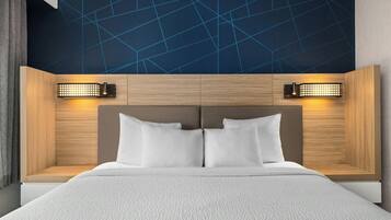 Habitación de hotel moderna con una cama grande, cabecero de madera y techo con un diseño geométrico.