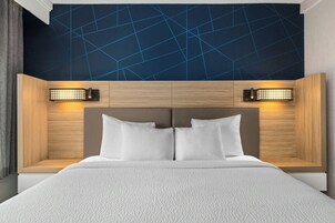 Habitación de hotel moderna con una cama grande, cabecero de madera y techo con un diseño geométrico.