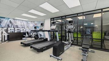 Ein Fitnessstudio mit Laufbändern, Crosstrainern und Gewichtsbänken.