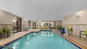 An indoor swimming pool with clear blue water, surrounded by green and black lounge chairs. - Springhill Suites By Marriott Minneapolis Eden Prairie (Eden Prairie)