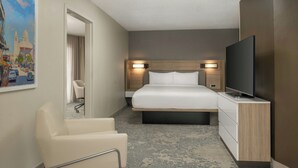 A hotel room with a bed, a TV, a desk, and a chair.