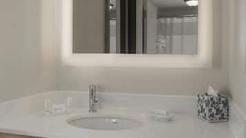 A modern bathroom with a white sink, a mirror with integrated lighting, and a wooden vanity with shelves for towels.