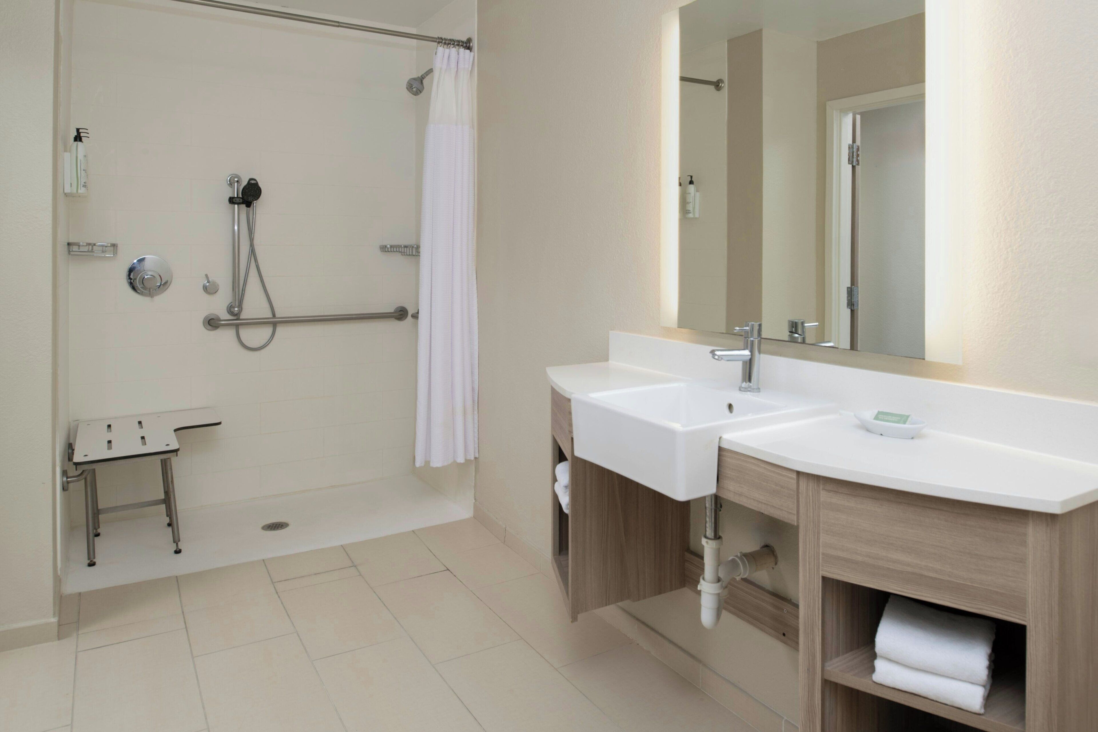 A modern bathroom with a shower, two sinks, a mirror, and a towel rack.