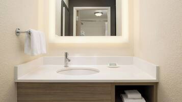 Un baño con un lavamanos blanco, un espejo y un perchero para toallas.
