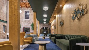 A lobby with a blue carpet, yellow and green sofas, and a brick wall.