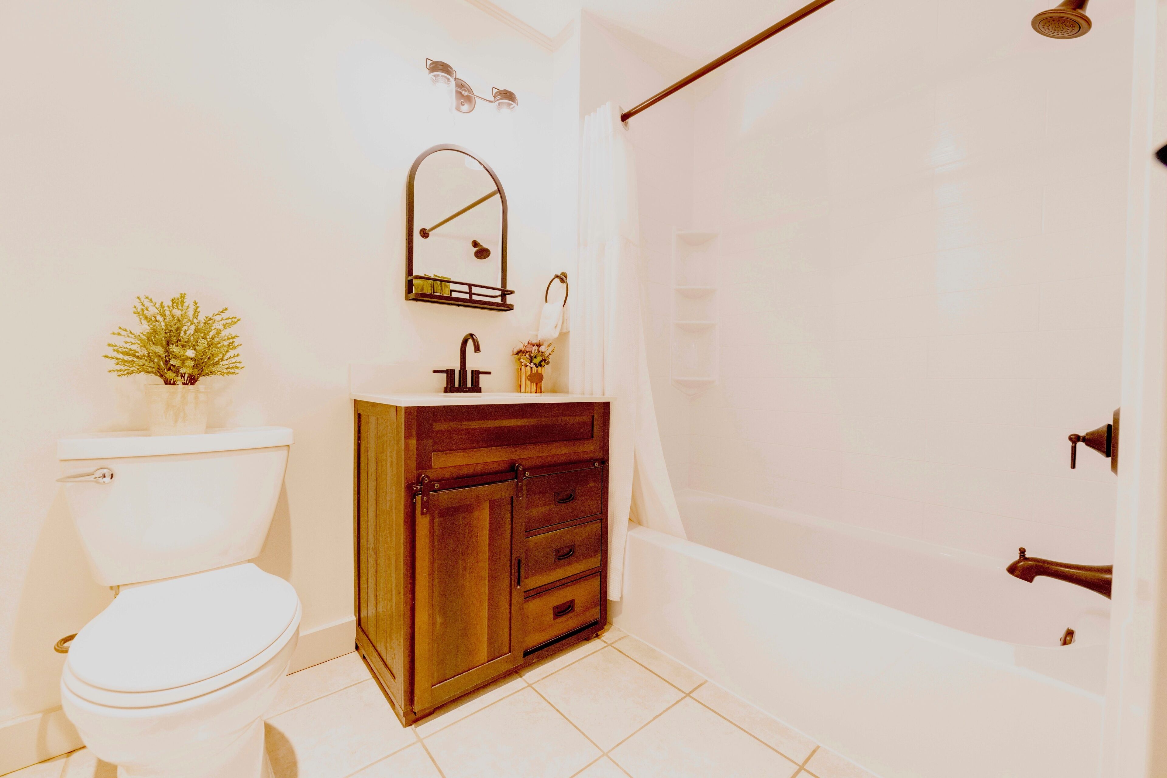 Une salle de bain comprenant des toilettes, un meuble en bois, un lavabo, un miroir et un espace douche.