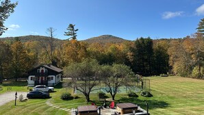 A cabin with a red door, a tennis court, and a mountain in the background. - Innsbruck Inn at Stowe (Stowe)