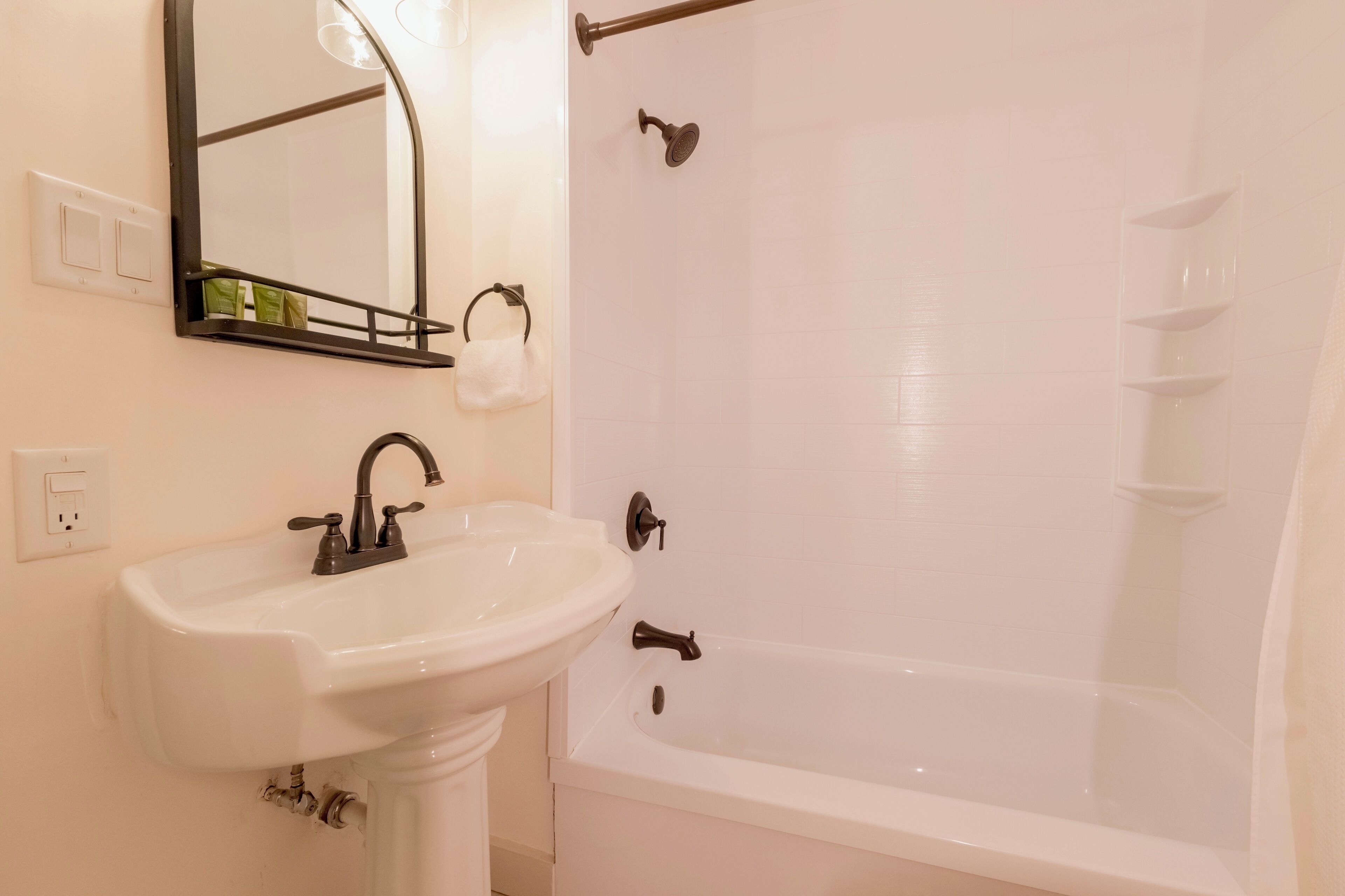 A bathroom with a white sink, a mirror, and a bathtub.