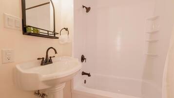 A bathroom with a white sink, a mirror, and a bathtub.
