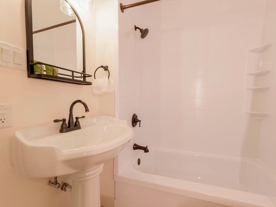 A bathroom with a white sink, a mirror, and a bathtub.