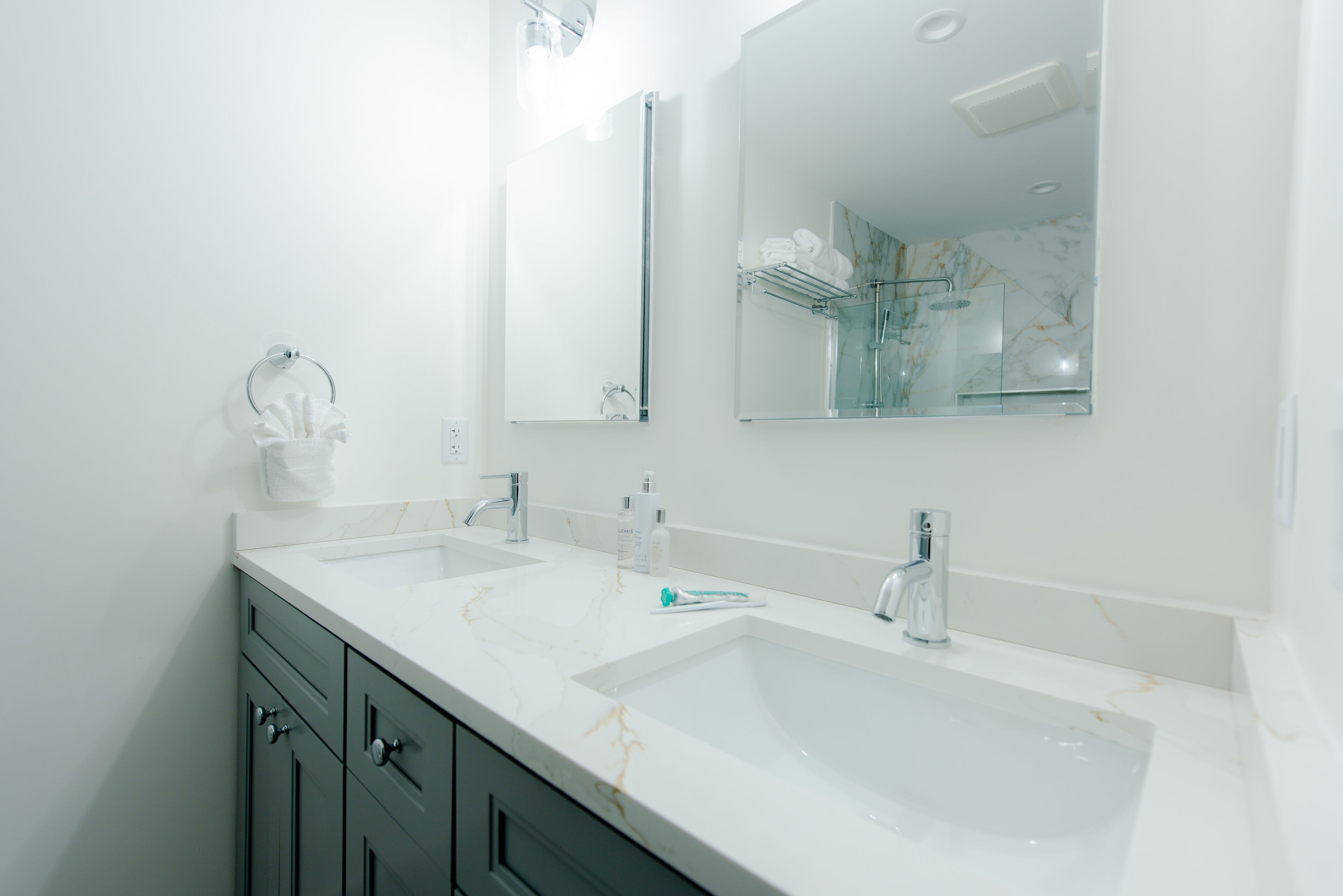 A modern bathroom with two sinks, a large mirror, and a glass shower enclosure.