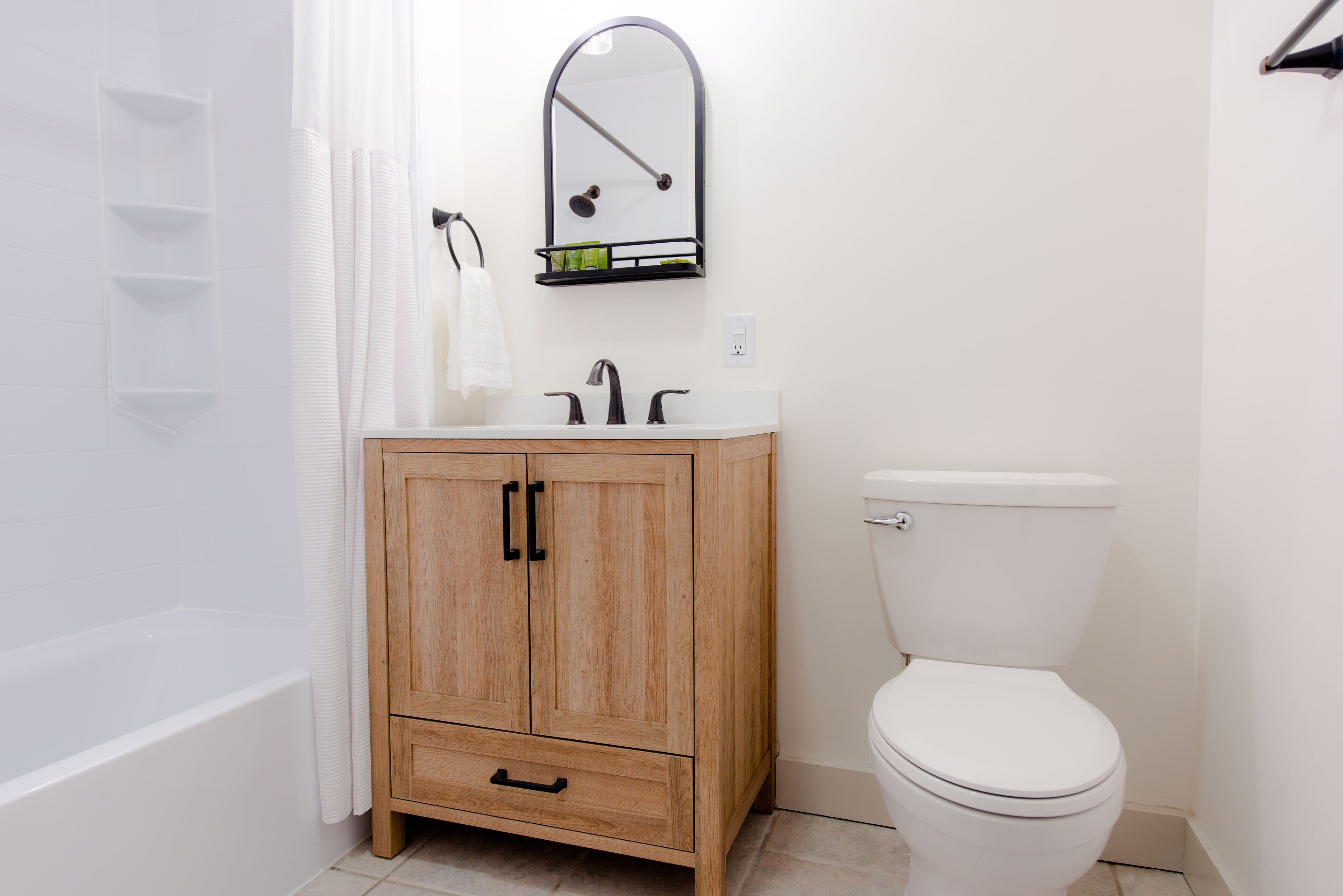 Une salle de bain avec un meuble en bois, un lavabo blanc, un miroir et des toilettes.