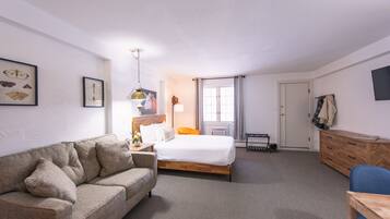 Une chambre d’hôtel avec un lit, un canapé, un bureau et une commode.