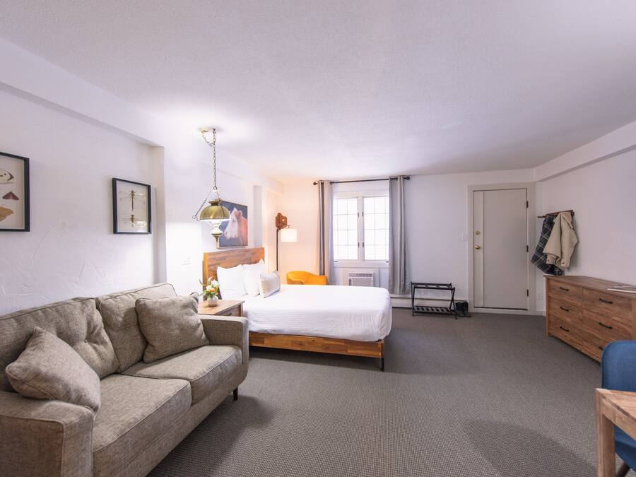 Une chambre d’hôtel avec un lit, un canapé, un bureau et une commode.