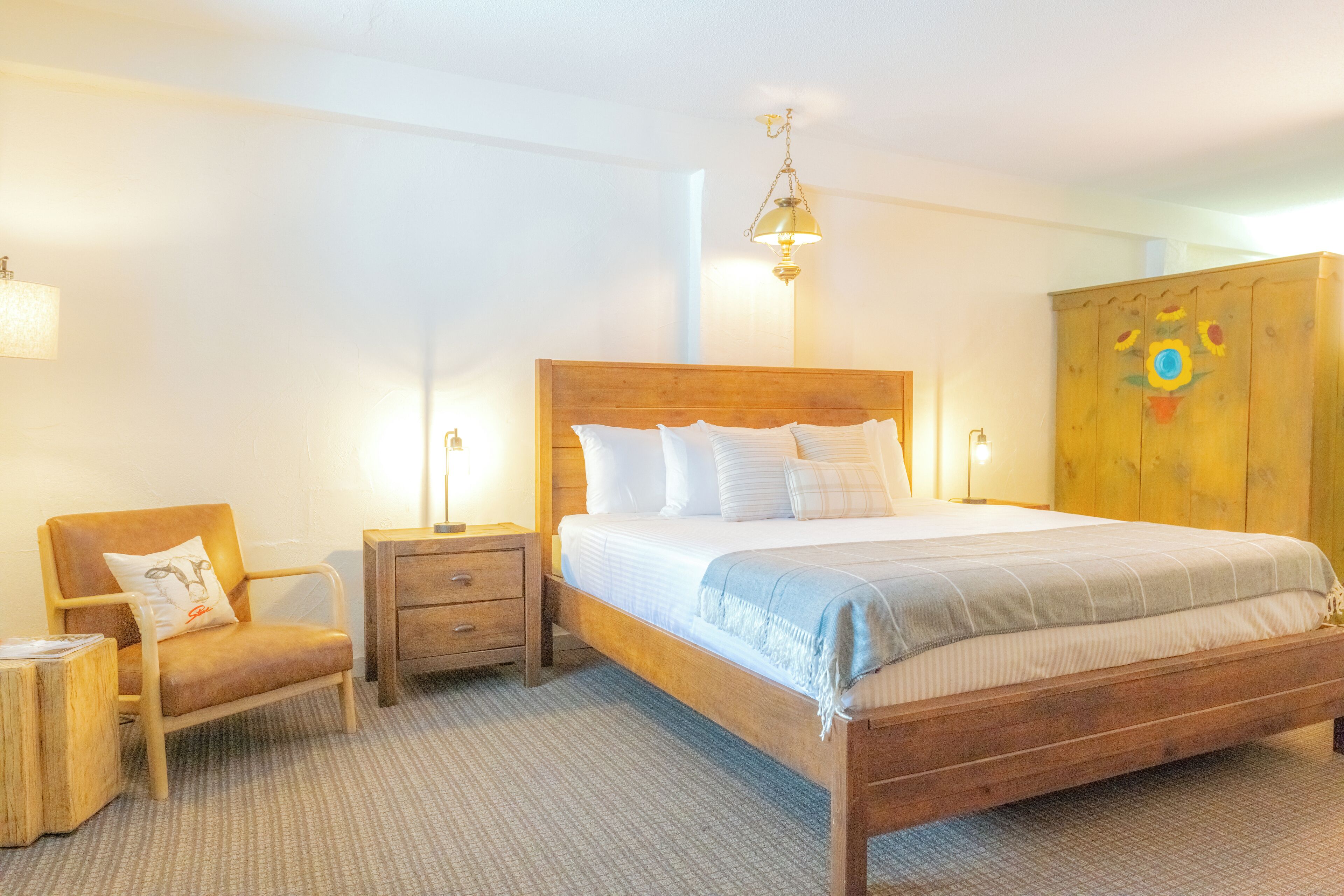 A bedroom with a wooden bed, a chair, a nightstand, and a wardrobe.