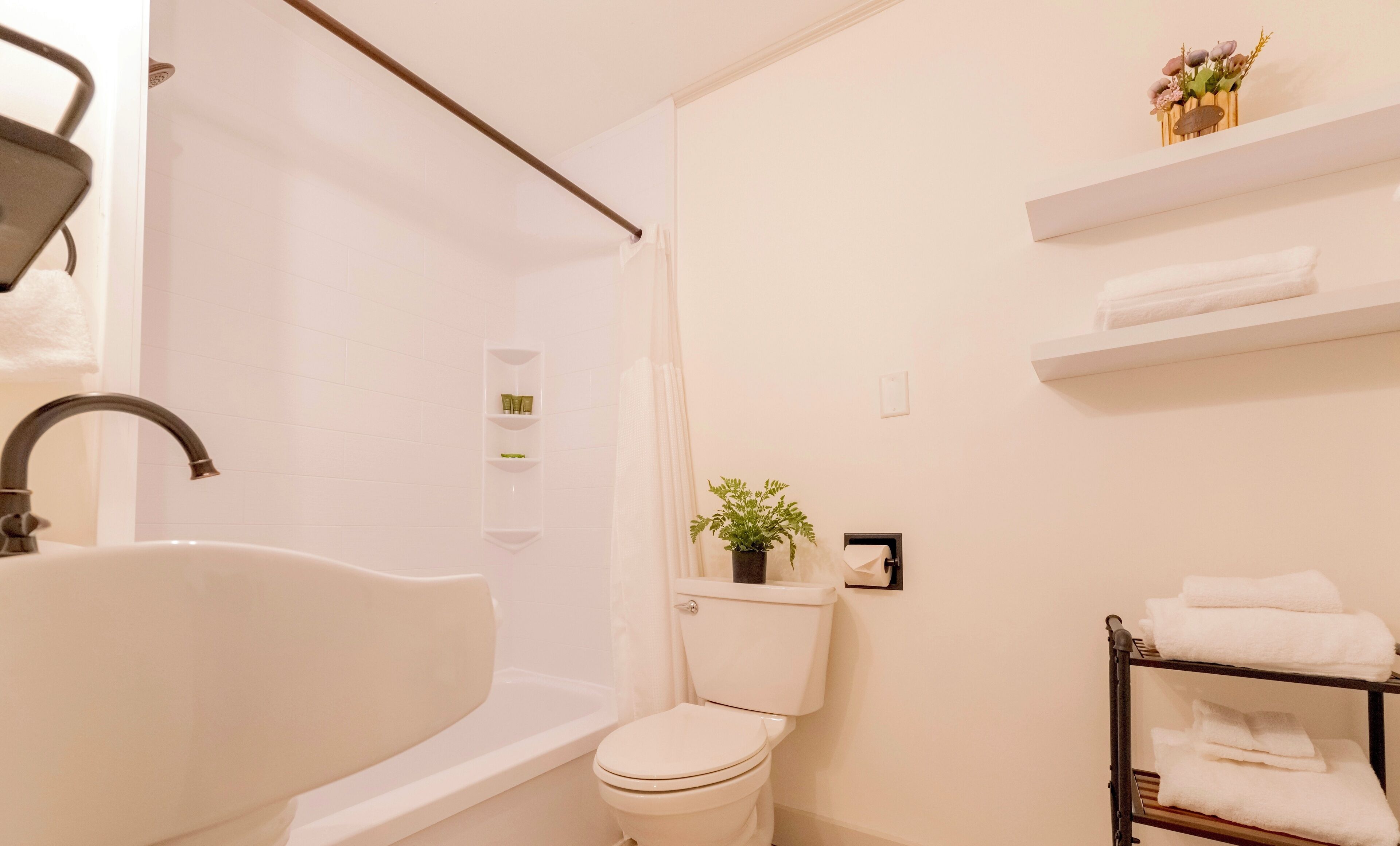 A bathroom with a bathtub, toilet, and a shelf with toiletries.