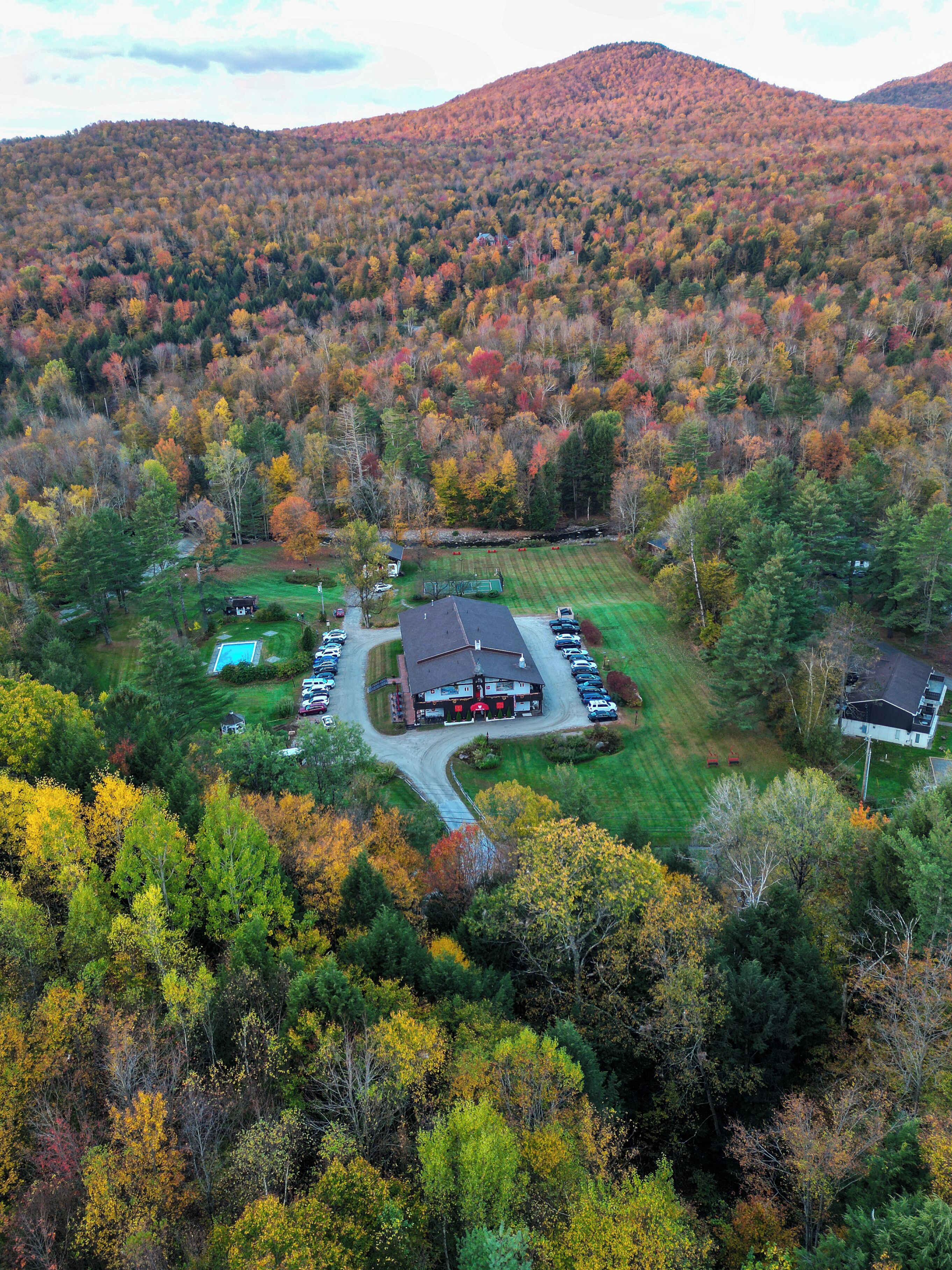 A lodge with a central building, parking lot, and surrounding forested area.