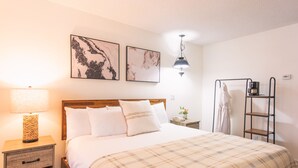 A neatly made bed with a plaid blanket, a bedside lamp, and two framed artworks on the wall. - Innsbruck Inn at Stowe (Stowe)