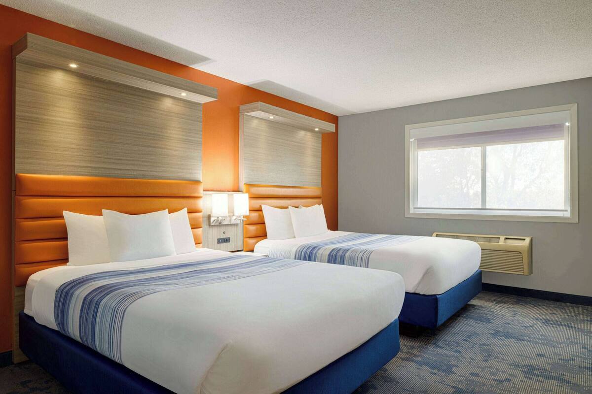 Een hotelkamer met twee bedden, een groot raam en een modern hoofdeinde.