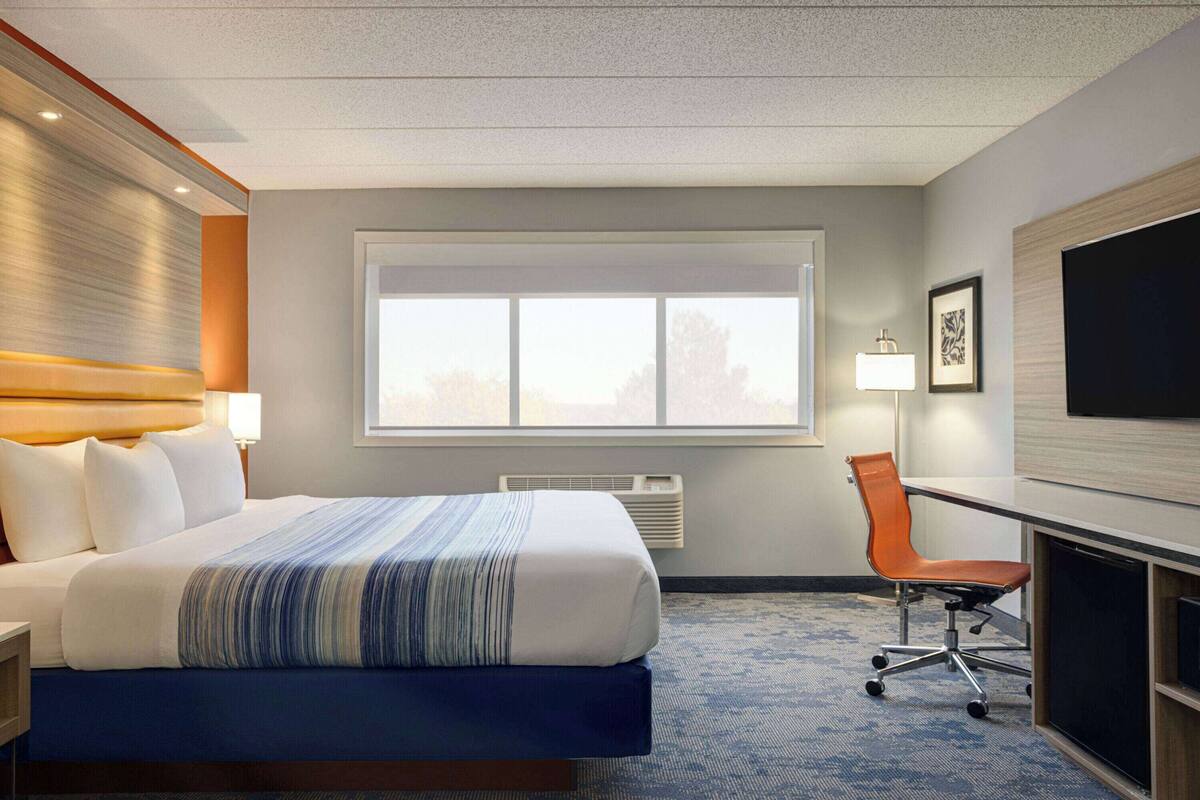 Een hotelkamer met een groot bed, een bureau met stoel, een televisie en een raam met uitzicht.