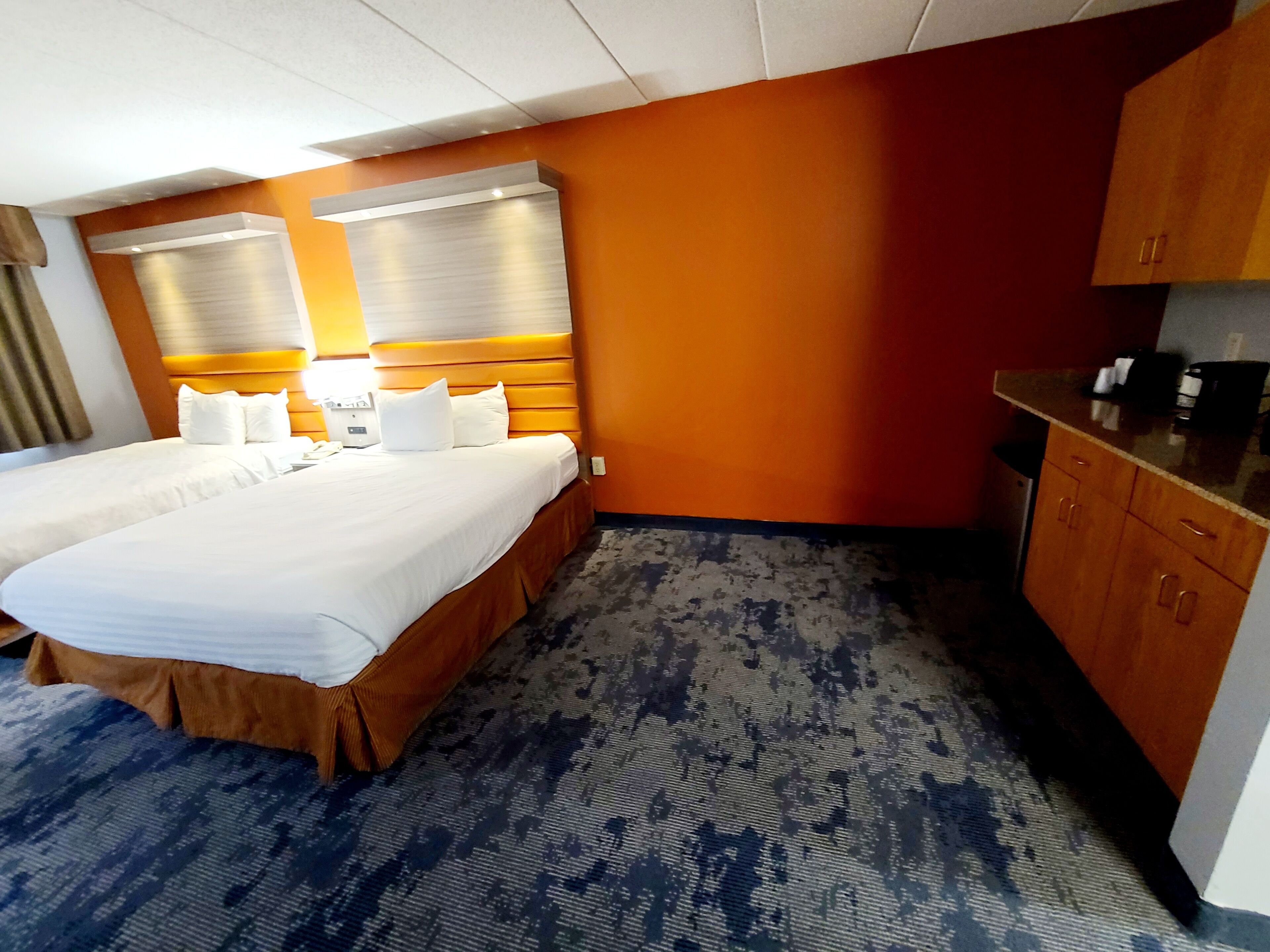 A hotel room with a large bed, a small kitchenette, and a carpeted floor.