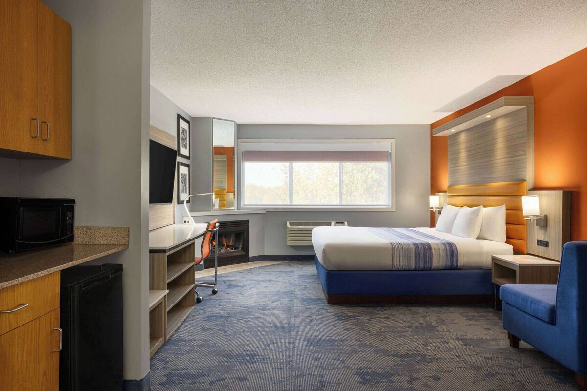 Een hotelkamer met een bed, een bureau, een magnetron, een stoel en een open haard.