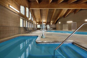 Una piscina interior con techo de madera y paredes de azulejos.