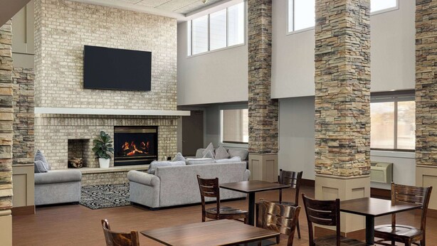 Un amplio salón con chimenea, un televisor de pantalla plana montado en la pared y una zona de estar con sofás y sillones.