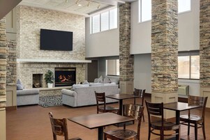 Un amplio salón con chimenea, un televisor de pantalla plana montado en la pared y una zona de estar con sofás y sillones.