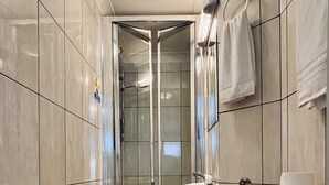 A modern bathroom with a toilet, sink, and glass shower enclosure. - West Cromwell Hotel (London)