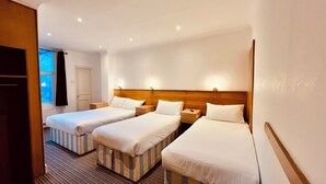 A hotel room with two single beds, a wooden headboard, bedside tables, and a window with curtains. - West Cromwell Hotel (London)