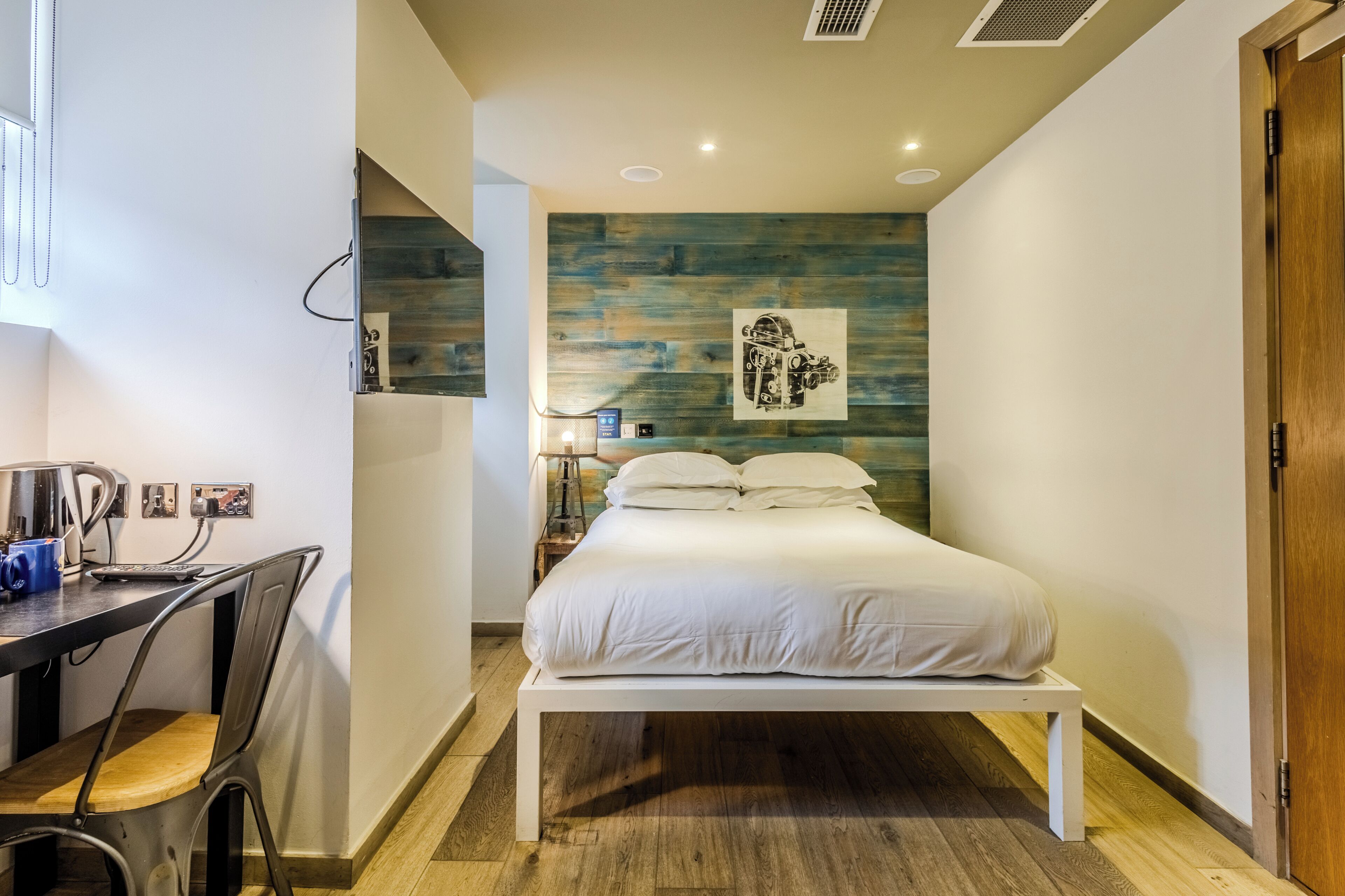 A bedroom with a bed, a desk, and a chair.