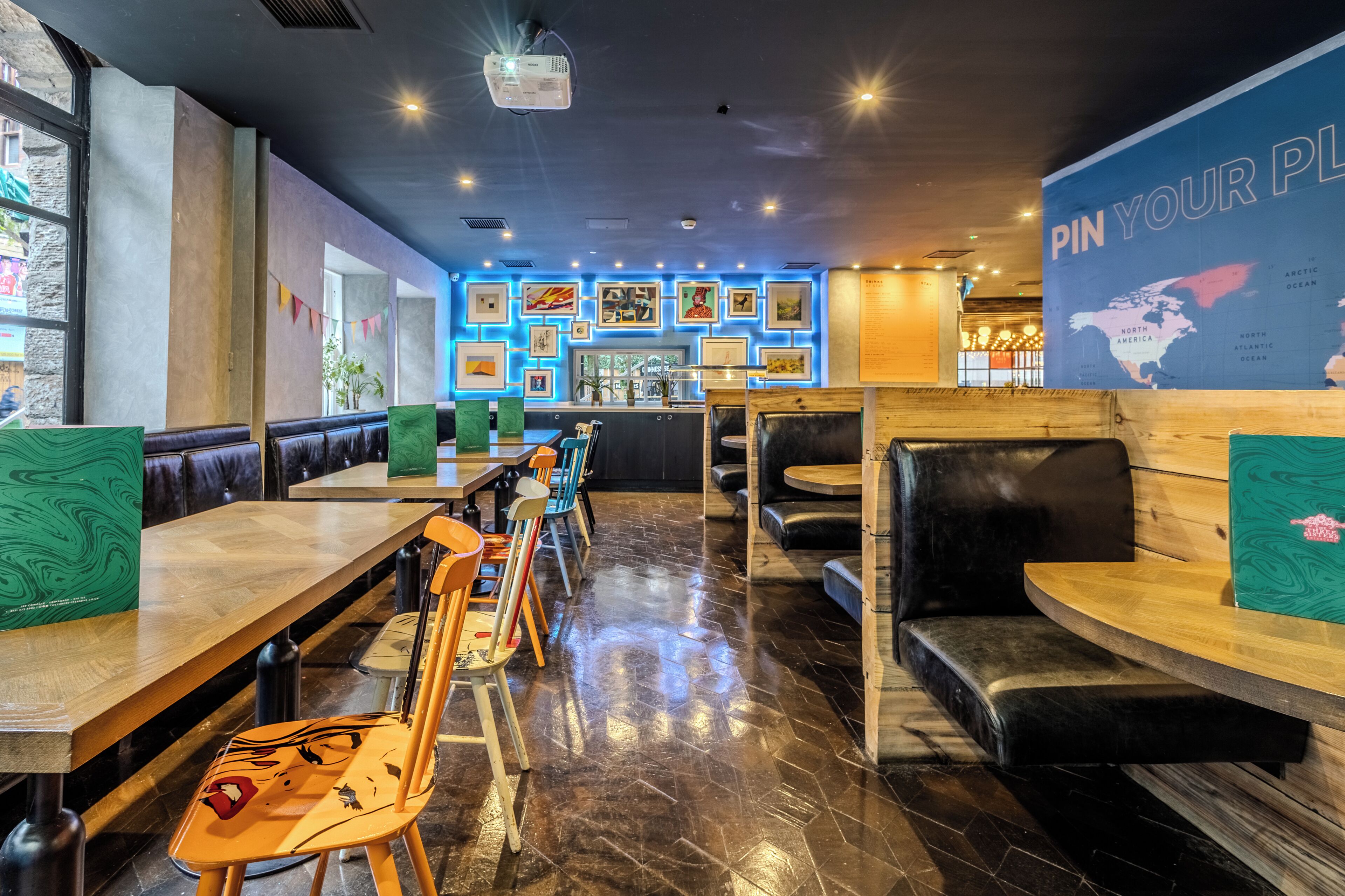 A restaurant interior with booths, tables, and a wall displaying various framed pictures.