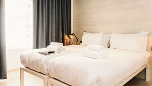 Een moderne hotelkamer met een groot bed, een nachtkastje met een lamp en een raam met gordijnen.