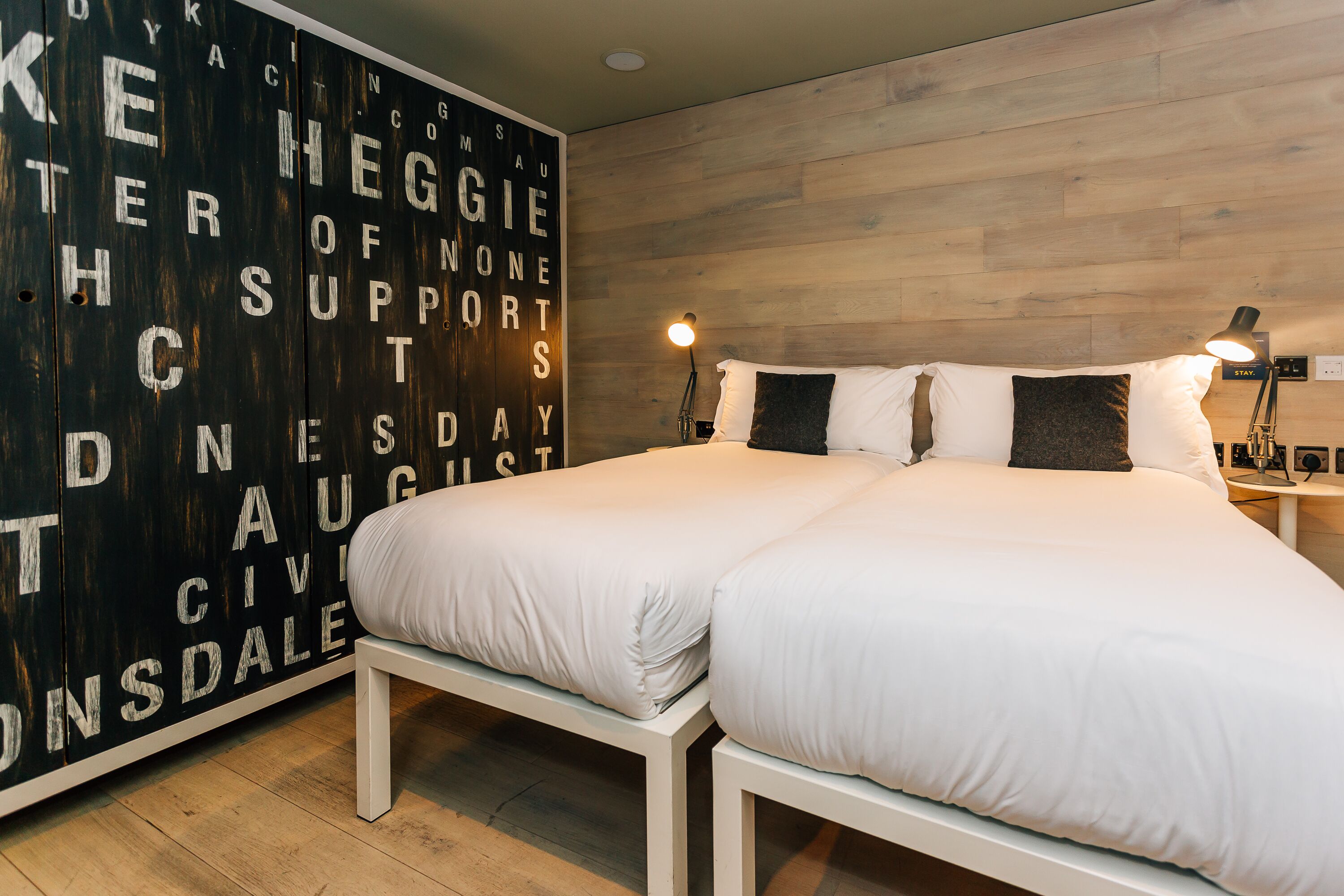 A bedroom with a large bed, two bedside tables, and a wall-mounted lamp.