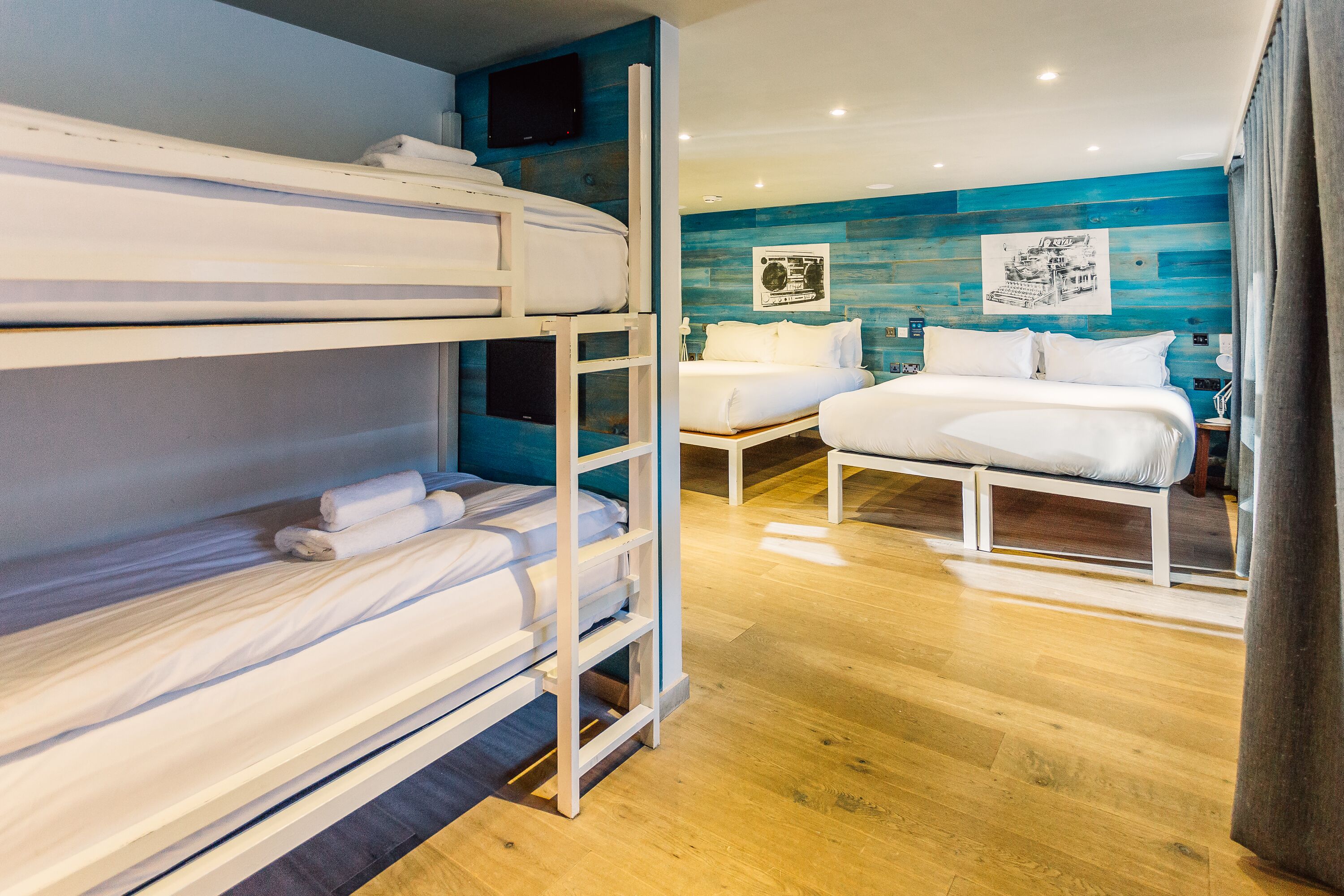 A hotel room with bunk beds, a bed, a desk, and a flat-screen TV.