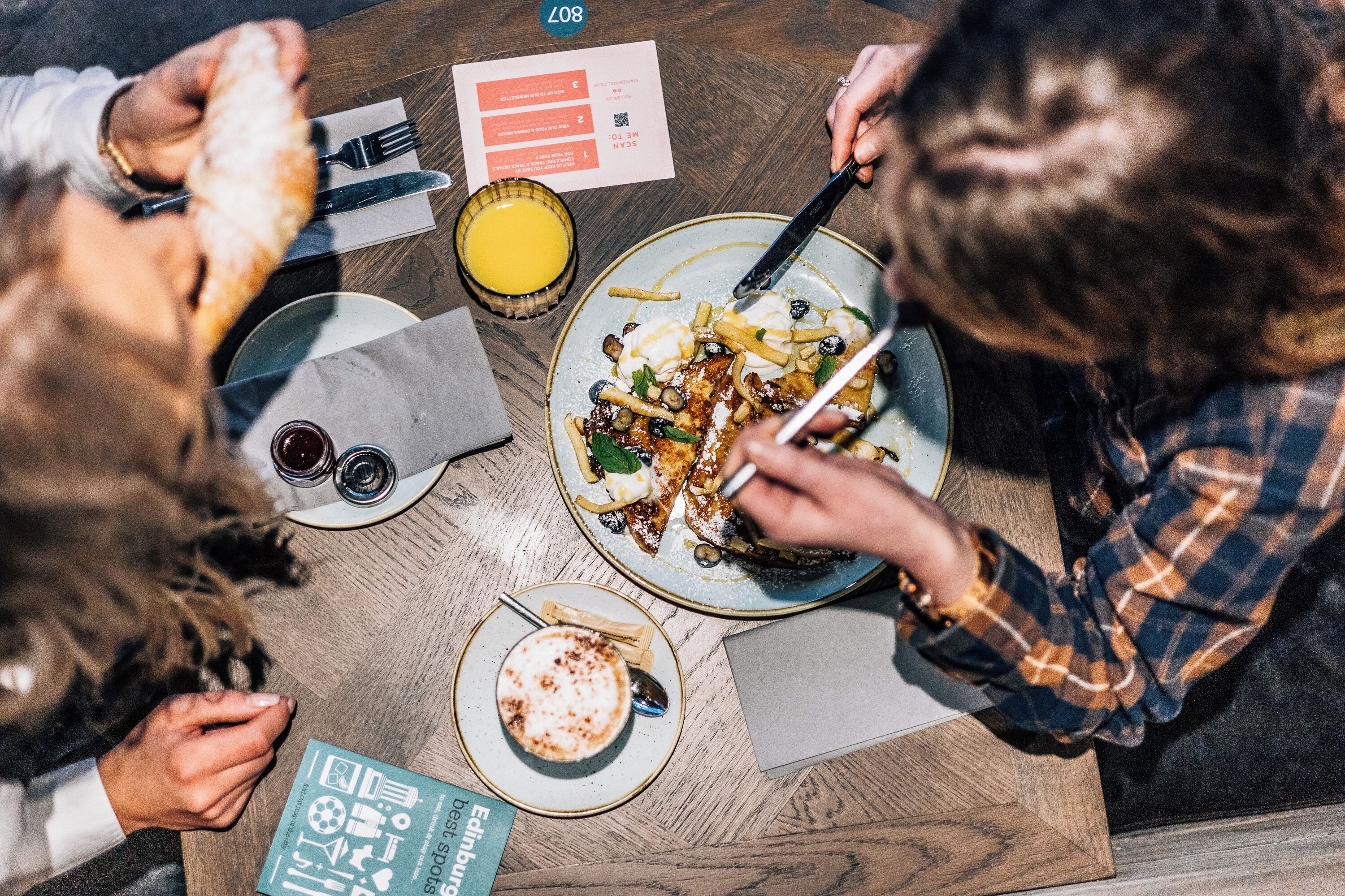 Una mesa de comedor con platos de comida, cubiertos y una carta.